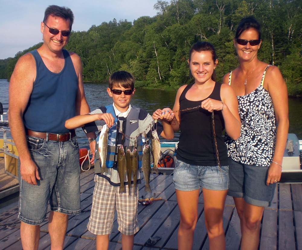 Mom, dad, daughter and son holding a stringer of rainbow trout they caught on Trout Lake in Minnesota.